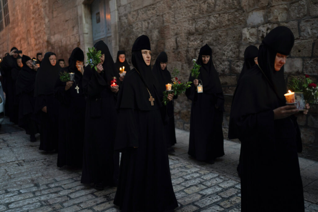 Christian Orthodox nuns hold candles and flowers as they walk in a procession to bring an icon of the Virgin Mary to the tomb where it is believed she is buried, along the streets of the Old City of Jerusalem, early on Friday, 25th August, 2023.