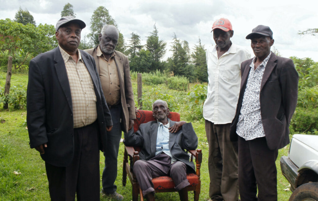 Kibore Cheruiyot Ngasura, 105, a member of the Talai community, which accuses the British colonial government of displacing them from their farms, pose for a picture with his sons outside his house ahead of Britain's King Charles' and Queen Camilla's visit to Kenya, in Tugunon village of Kericho County, Kenya, on 25th October, 2023