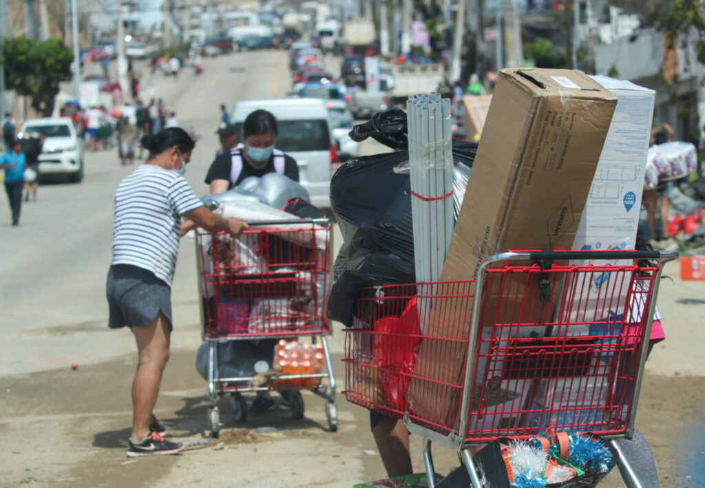 People leave with goods they took from a supermarket that had been broken into, in the aftermath of Hurricane Otis in Acapulco, Mexico, on 26th October, 2023