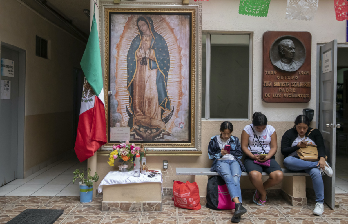 Migrants use their cell phones at the Casa del Migrante Catholic refugee shelter decorated with Our Lady of Guadalupe in Tijuana, Mexico, on Tuesday, 26th September, 2023