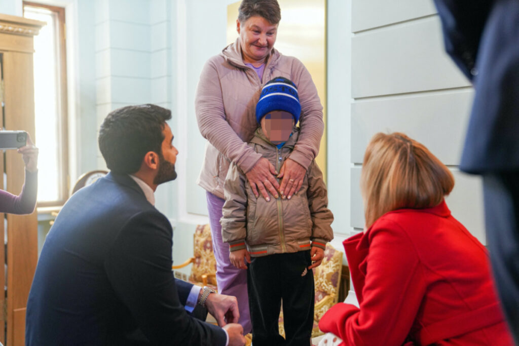 A seven-year-old Ukrainian boy, who is the first child released under a new mechanism Qatar has set up with the goal of repatriating children from Russia to Ukraine, stands with his grandmother while interacting with Russia's Commissioner for Children's Rights, Maria Lvova-Belova and a Qatari diplomat in this handout image taken at Qatar's embassy in Moscow, Russia, on 13th October, 2023.