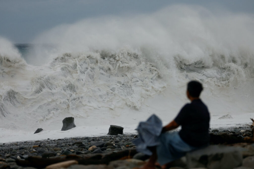 A woman sits by the shore while looking at waves breaking as Typhoon Koinu approaches, in Taitung, Taiwan on 4th October, 2023