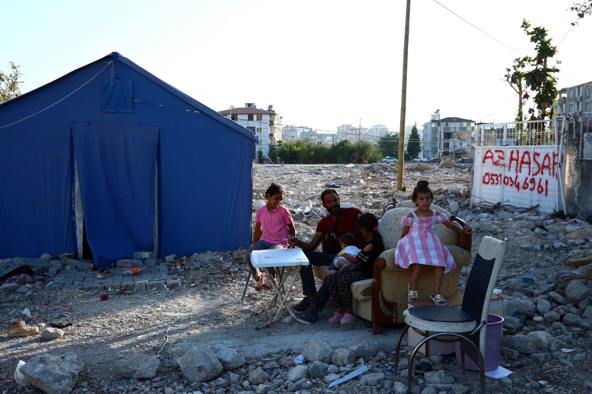 Ammar, a Syrian earthquake survivor, chats with his children outside their tent in Antakya, Turkey, on 9th September, 2023