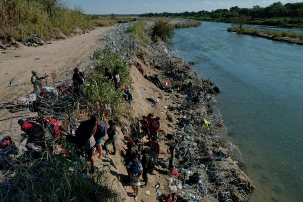 Members of the Texas National Guard try to dissuade migrants from climbing over the razor wire after they crossed the Rio Grande in Eagle Pass, Texas, US, on 29th September, 2023.