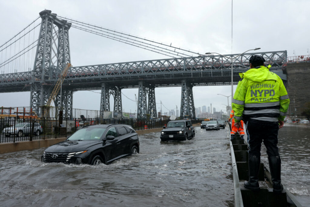 A police officer from the NYPD Highway Patrol looks on as motorists drive through a flooded street after heavy rains as the remnants of Tropical Storm Ophelia bring flooding across the mid-Atlantic and Northeast, at the FDR Drive in Manhattan near the Williamsburg Bridge, in New York City, US, on 29th September, 2023