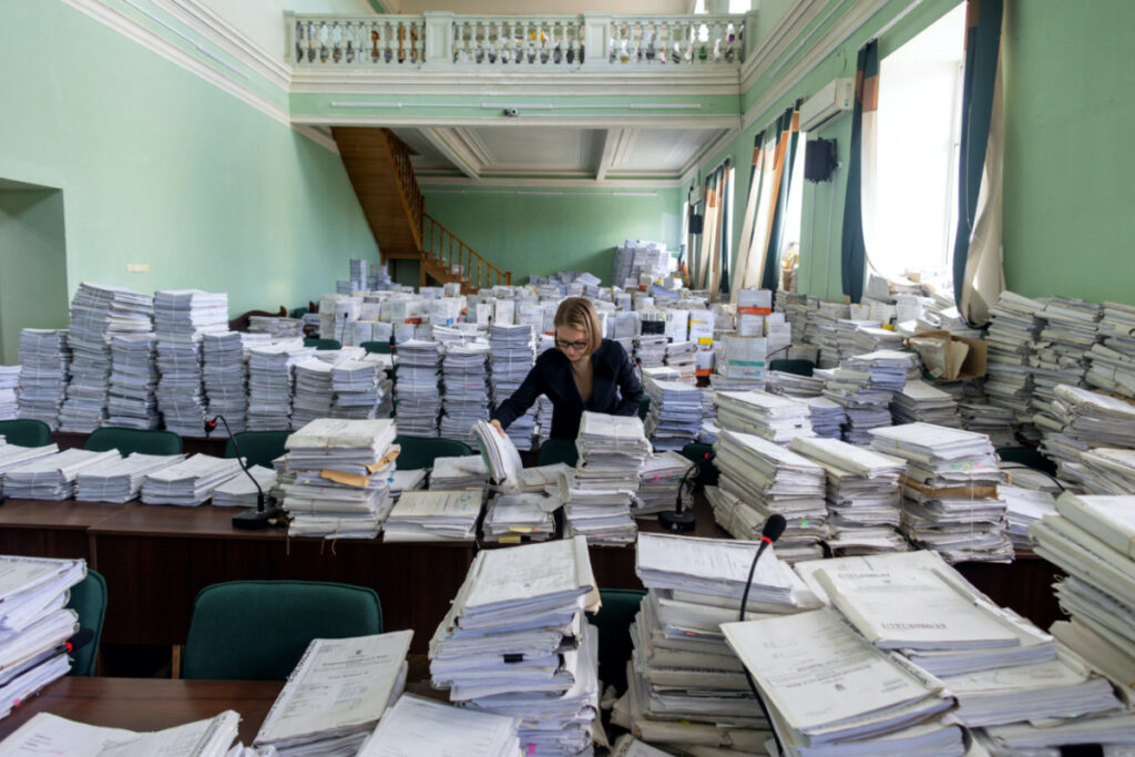 An employee looks through court documents in a former court room that was repurposed to an archive at the Pecherskyi District Court of Kyiv City in Kyiv, amid Russia's attack on Ukraine, on 17th October, 2023