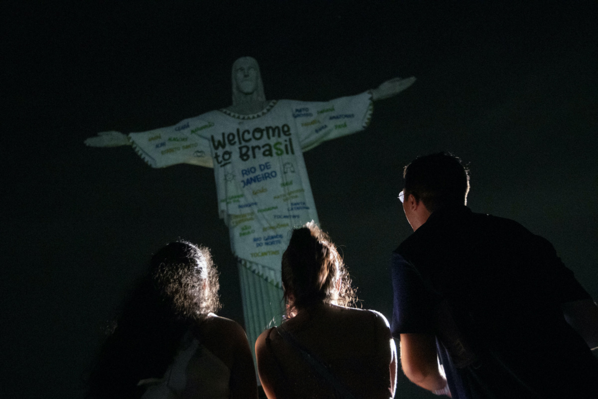 Fans look up at the Christ the Redeemer statue that is illuminated with a welcome message to American singer Taylor Swift, in Rio de Janeiro, Brazil, on Thursday, 16th November, 2023.