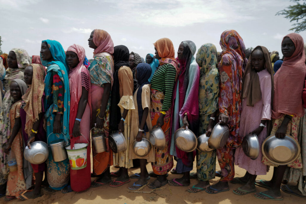 Sudanese women who fled the conflict in Geneina in Sudan's Darfur region, line up to receive rice portions from Red Cross volunteers in Ourang on the outskirts of Adre, Chad, on 25th July, 2023
