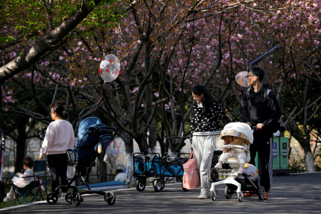 A parents pushes a stroller with a baby in a park in Shanghai, China, on 2nd April, 2023