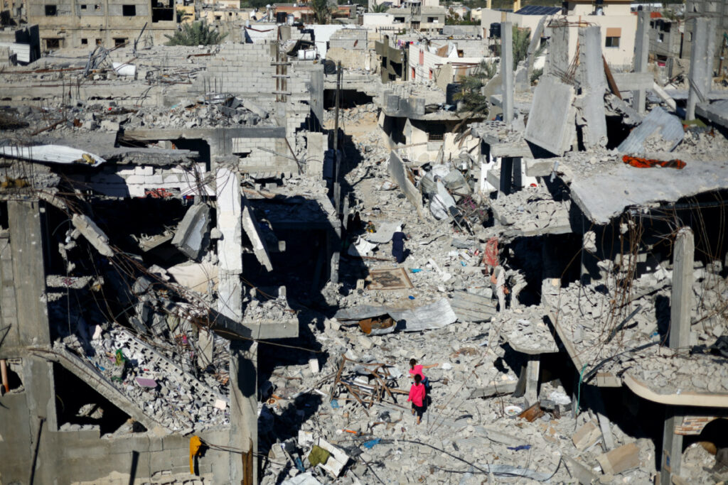 Palestinian children walk among the houses destroyed in Israeli strikes during the conflict, amid the temporary truce between Israel and the Palestinian Islamist group Hamas, at Khan Younis refugee camp, in the southern Gaza Strip, on 29th November, 2023
