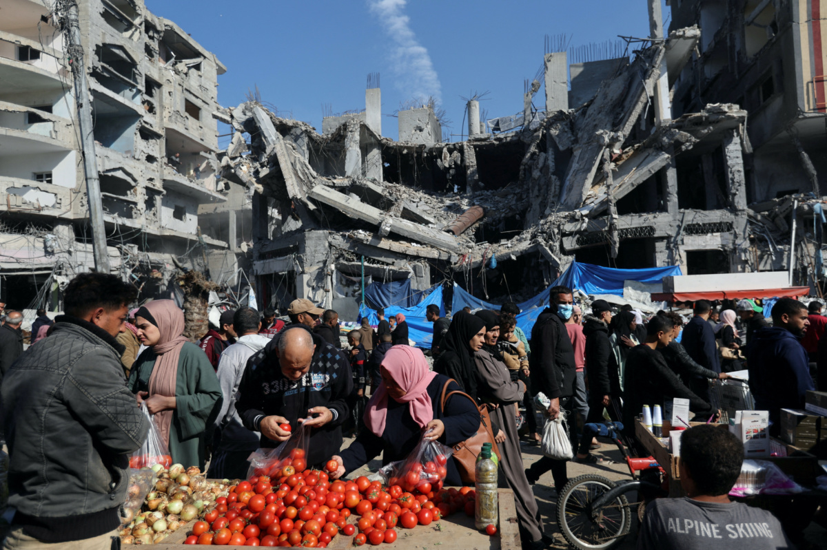 Palestinians shops in an open-air market near the ruins of houses and buildings destroyed in Israeli strikes during the conflict, amid a temporary truce between Hamas and Israel, in Nuseirat refugee camp in the central Gaza Strip on 30th November, 2023
