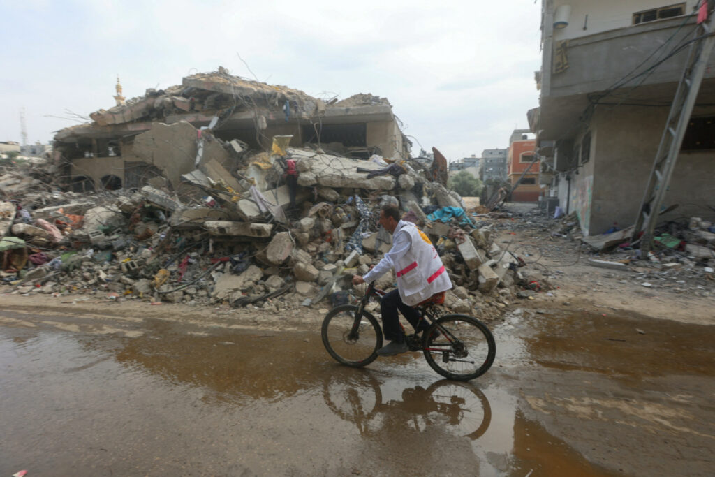 Palestinian doctor Hassan Zain al Din, who travels on his bicycle from one makeshift shelter to another to provide treatment and medication to displaced patients, rides past the rubble amid fuel shortages, as the conflict between Hamas and Israel continues, in Deir al-Balah, in the central Gaza Strip, on 29th October, 2023