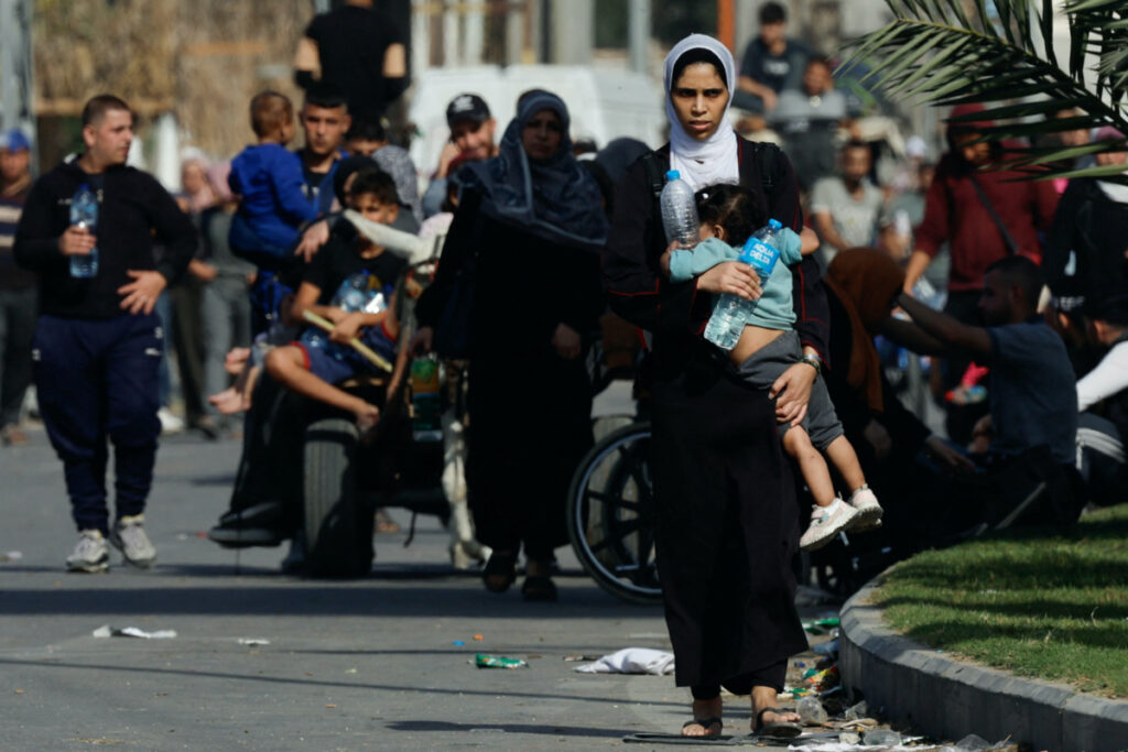 A woman carries a child as Palestinians fleeing north Gaza walk towards the south, amid the ongoing conflict between Israel and Palestinian Islamist group Hamas, in the central Gaza Strip, on 9th November, 2023