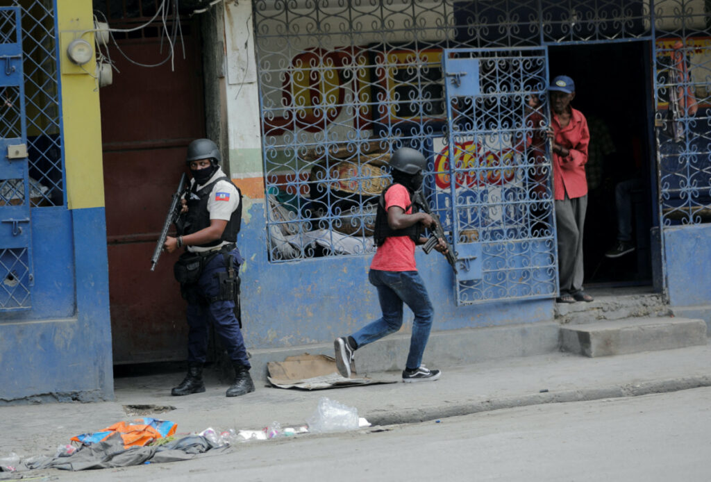 A man looks out of a store as police patrol the streets after gang members tried to attack a police station, in Port-au-Prince, Haiti, on 25th April, 2023