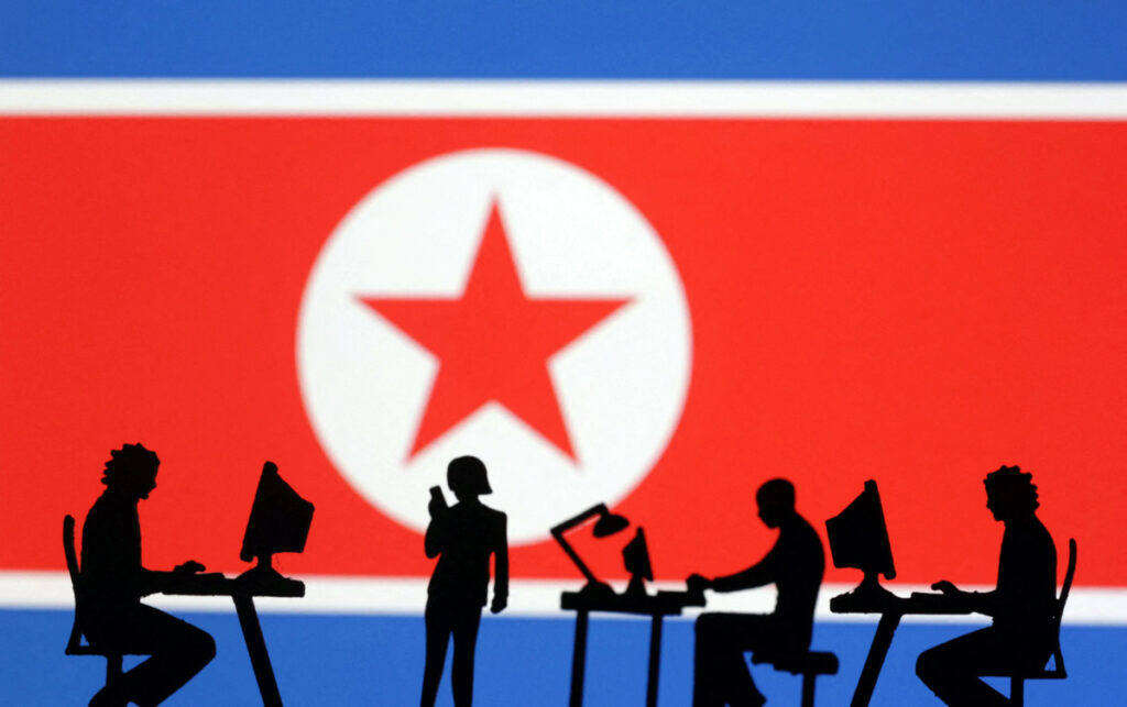 People with computers are seen in front of North Korea flag in this illustration