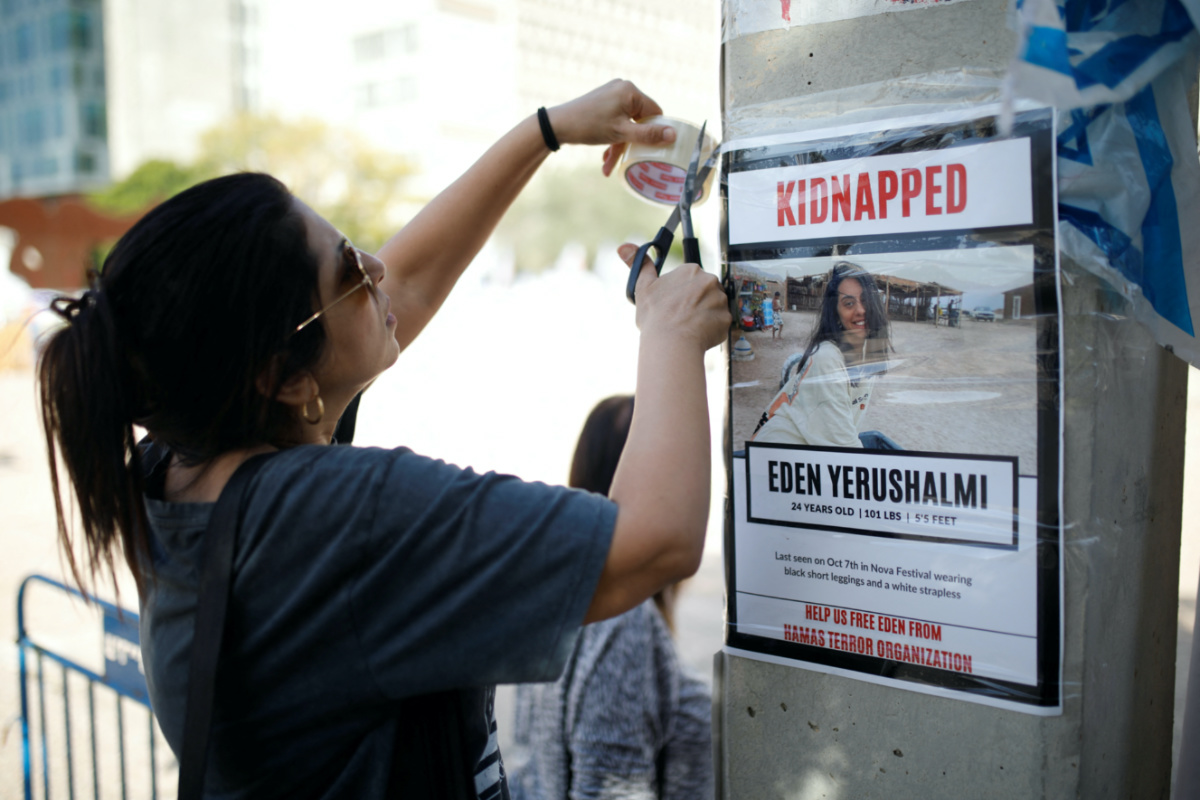 A woman tapes a poster to a wall, calling for the release of Eden Yerushalmi, who was taken hostage on 7th October during the deadly attack by Palestinian Islamist group Hamas, at the so-called "Hostages Square" in Tel Aviv, Israel on 23rd November, 2023