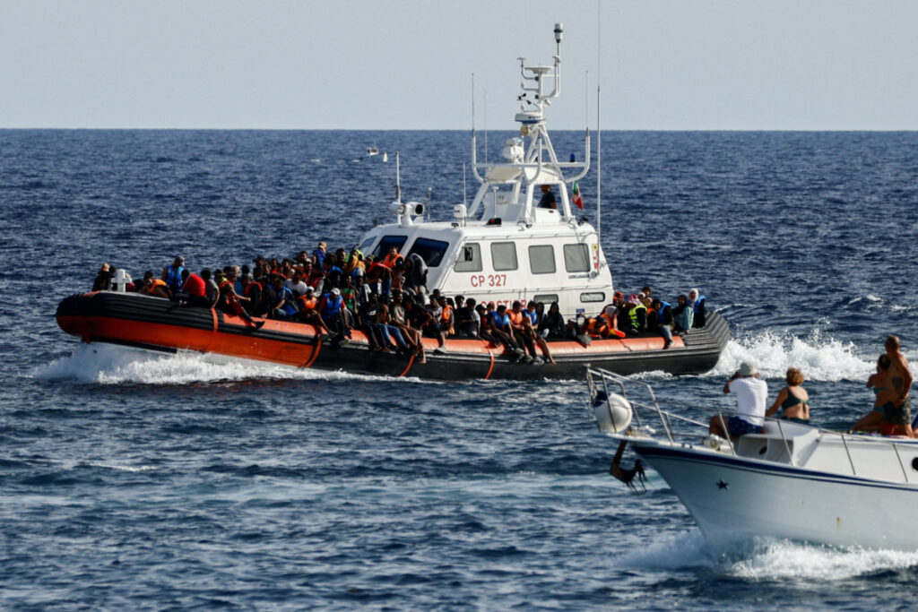 An Italian Coast Guard vessel carrying migrants rescued at sea passes near a tourist boat, on the Sicilian island of Lampedusa, Italy, on 18th September, 2023