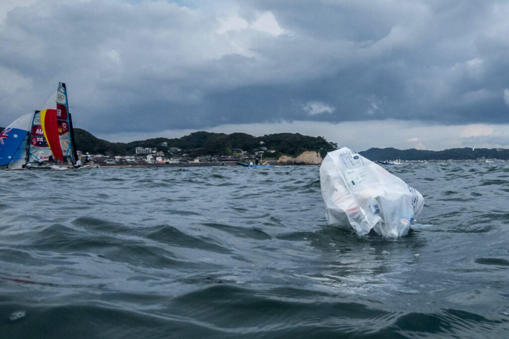 A plastic bag containing trash floats on the water as competitors warm up for their race.