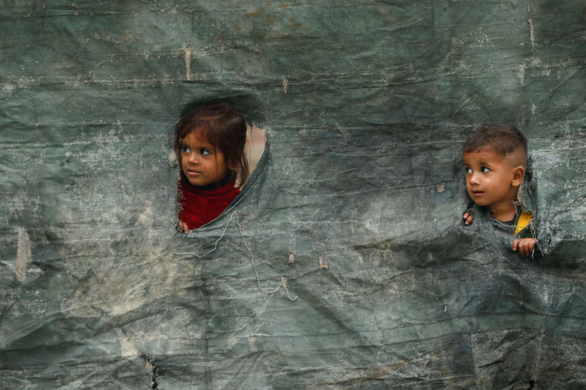 Children from an Afghan family look outside from a torn tent as they along with their family are returning home, after Pakistan gives the last warning to undocumented immigrants to leave, outside the United Nations High Commissioner for Refugees repatriation centres in Azakhel town in Nowshera, Pakistan on 1st November, 2023