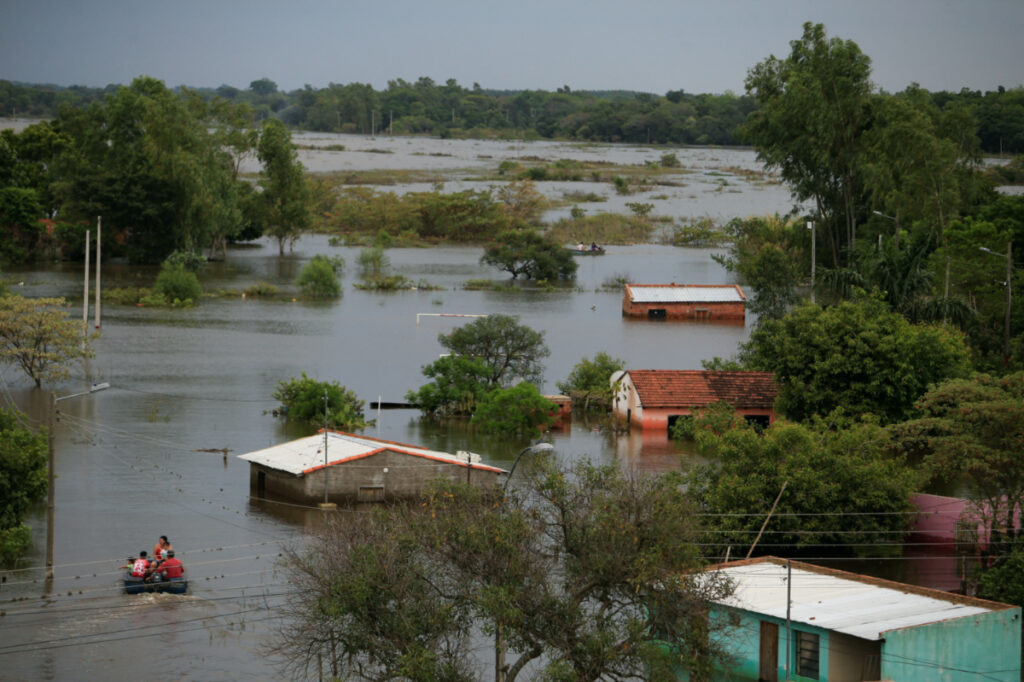 People ride in a boat in a flooded area after the Parana river overflowed its banks due to heavy rain upstream, in Ayolas, Paraguay, on 8th November, 2023