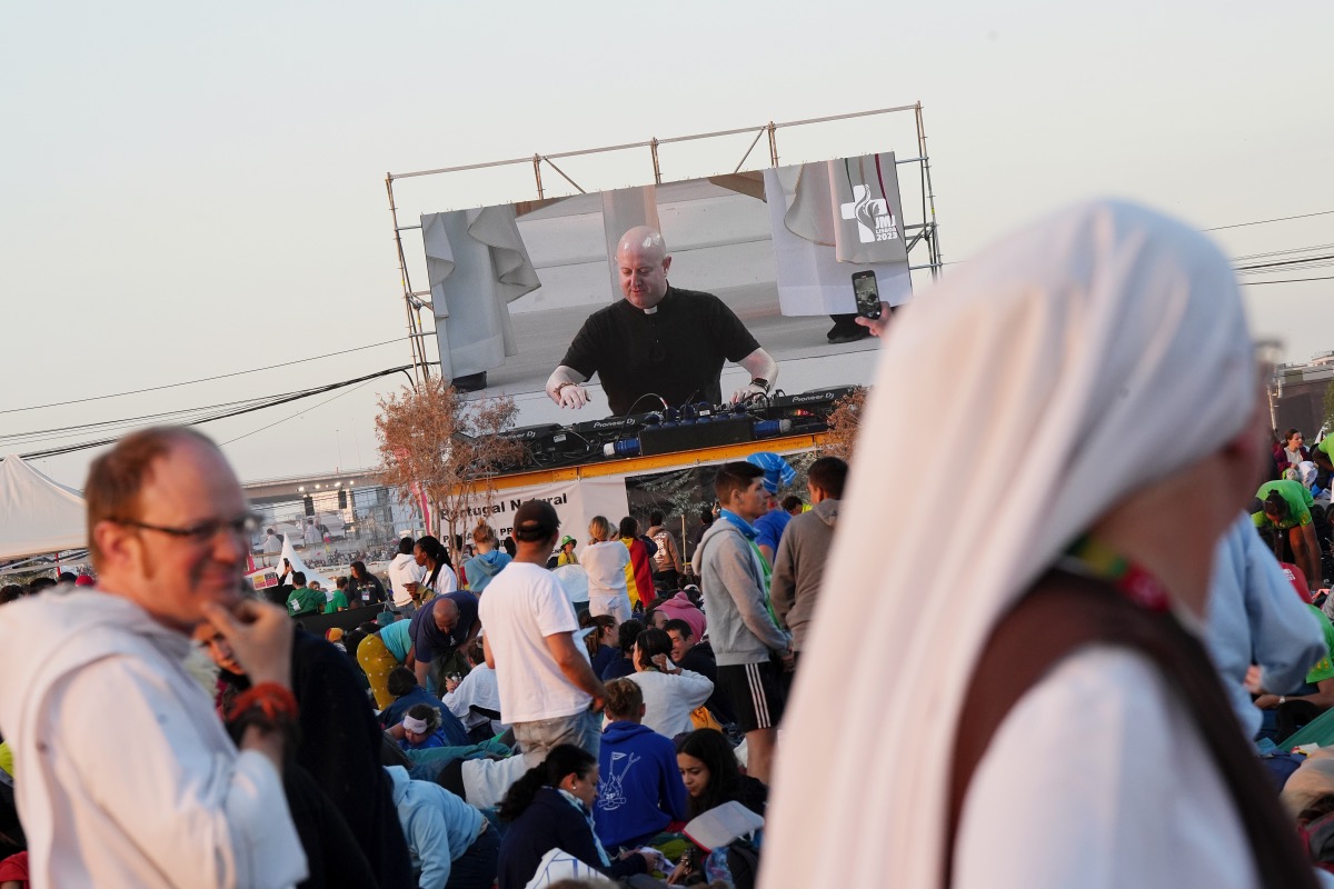 Roman Catholic priest Guilherme Peixoto, on video screen, plays techno music to help pilgrims wake up at Parque Tejo in Lisbon on Sunday, 6th August, 2023