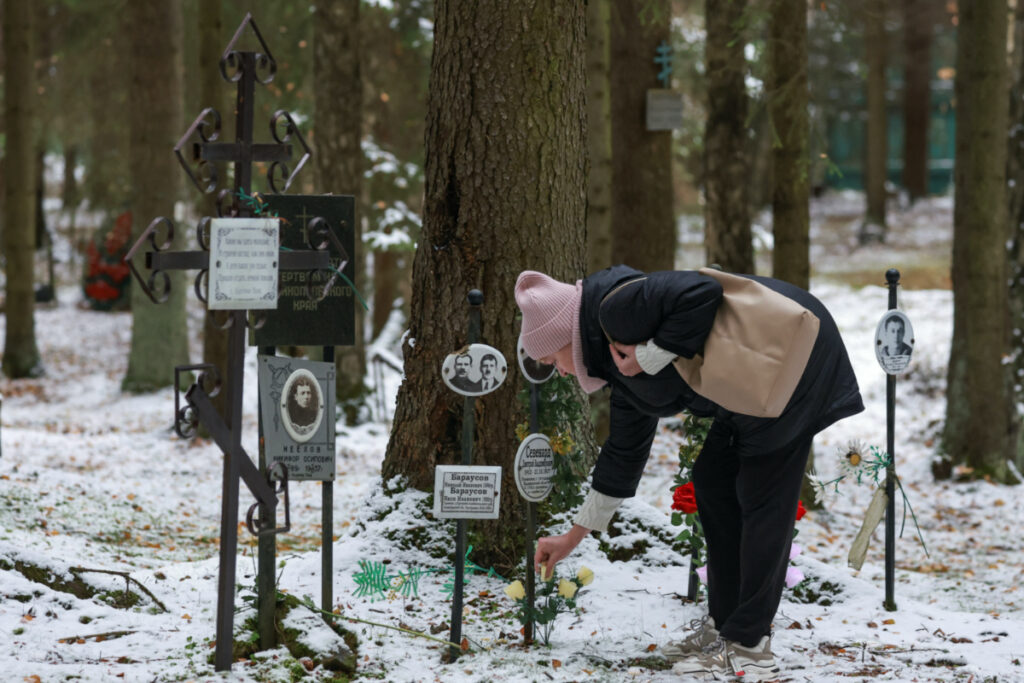A woman keeps a flower next to the grave of a victim of political repression between 1937 and 1954, at Levashovo Memorial cemetery on the outskirts of Saint Petersburg, Russia, on 30th October, 2023.