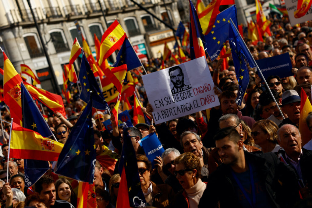 People hold flags as they take part in a protest called for by the Popular Party against a deal reached by Spain's socialists with the Catalan separatist Junts party for government support, which involves amnesties for people involved with Catalonia's failed 2017 independence bid, in Madrid, Spain, on 12th November, 2023.
