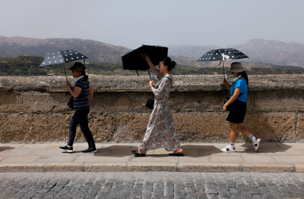 South Korean tourists shield themselves from the strong sun with umbrellas during Spain's third heatwave of the summer, in Ronda, Spain, on 9th August, 2023