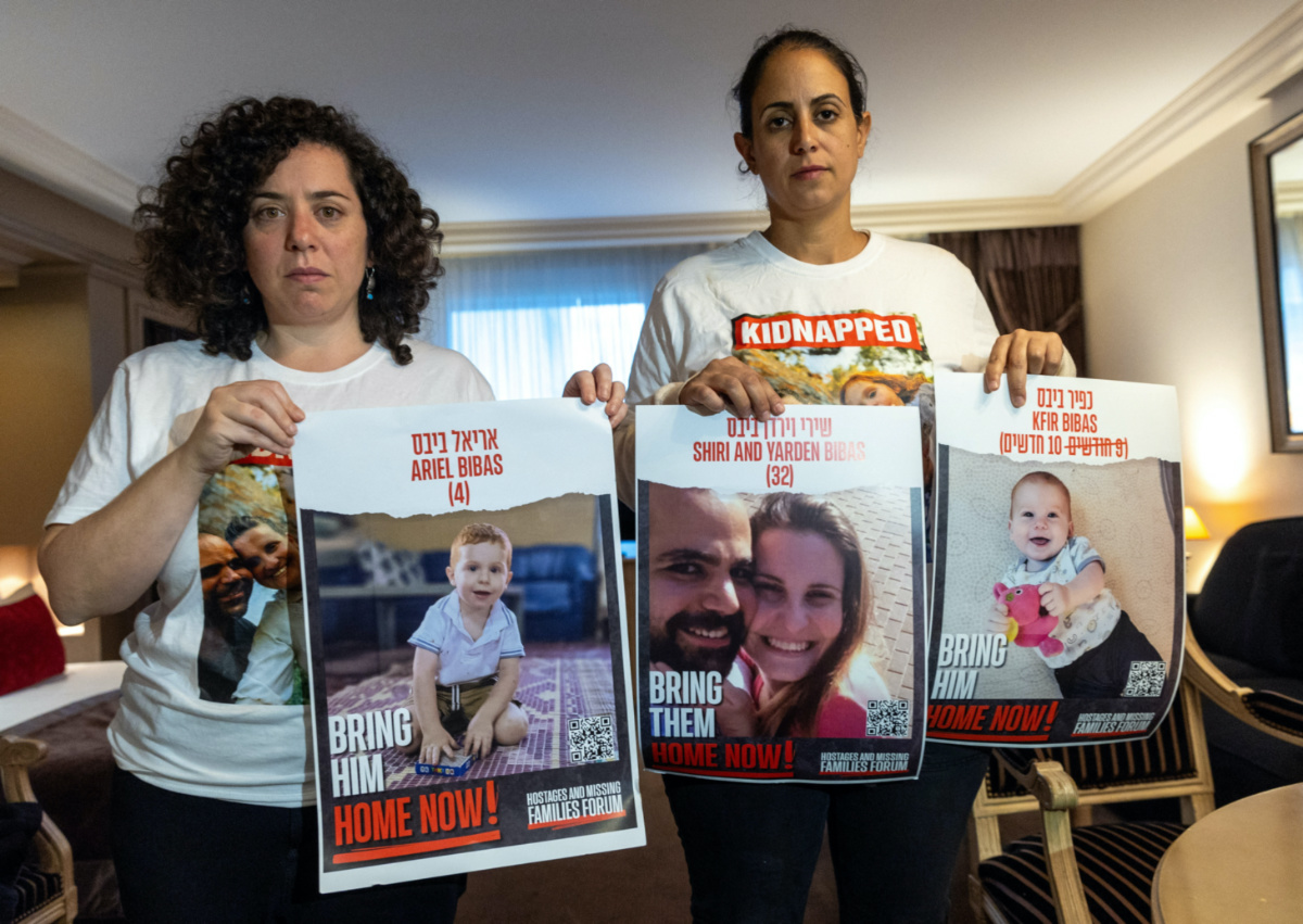 Ofri Bibas Levy, whose brother Yarden, 34, was taken hostage with his wife Shiri, 32, and two children Kfir, 10 months, and Ariel, 4,  holds with her friend Tal Ulus pictures of them during an interview with Reuters, as the conflict between Israel and the Palestinian Islamist group Hamas continues, in Geneva, Switzerland, on 13th November, 2023