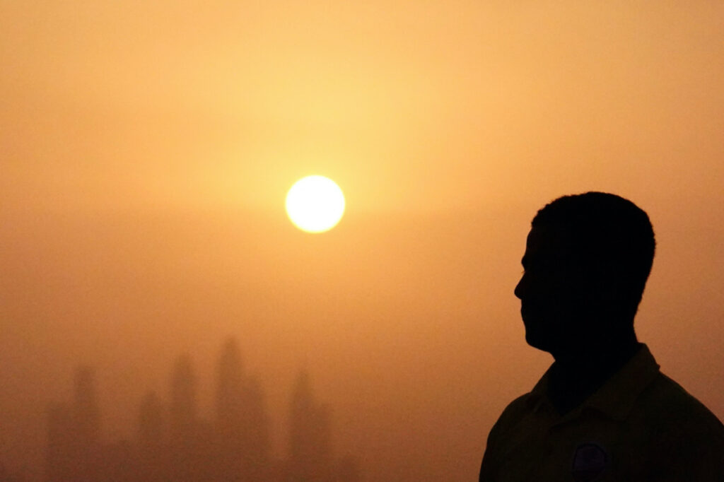 Lifeguard Mohamed stands near a swimming pool while the sun sets over Dubai, United Arab Emirates, on 12th August, 2023.