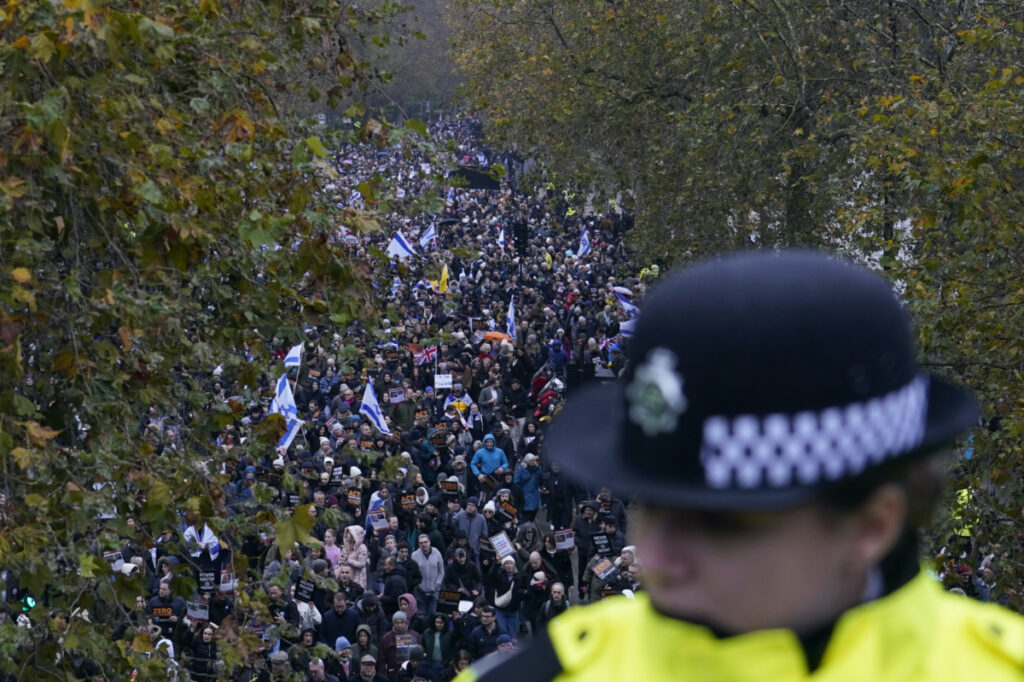 A policewoman stand guard on a bridge as an anti-Semitism demonstration with protesters holding placards flags and banners, including the flag of Israel, takes place in London, on Sunday, 26th November, 2023
