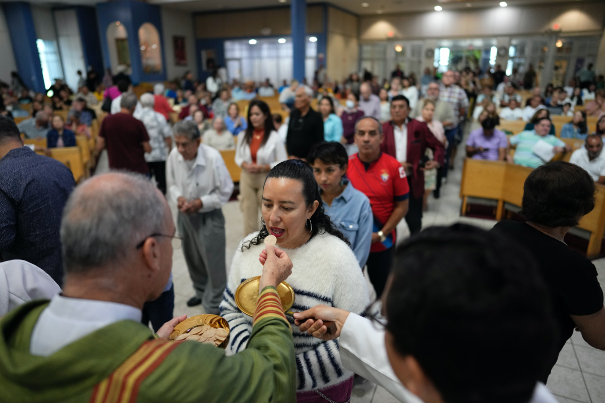 Rev Edwing Roman gives communion to parishioners during Mass at St Agatha Catholic Church, which has become the spiritual home of the growing Nicaraguan diaspora, on Sunday, 5th November, 2023, in Miami.