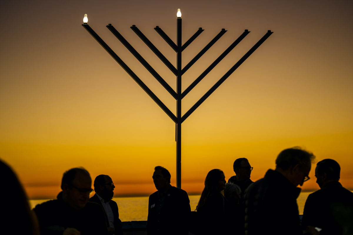 People gather around the 10-foot menorah during the "Hanukkah on the Pier" event at the end of the San Clemente pier hosted by Chabad of San Clemente in San Clemente, California, on Sunday, 18th December, 2022
