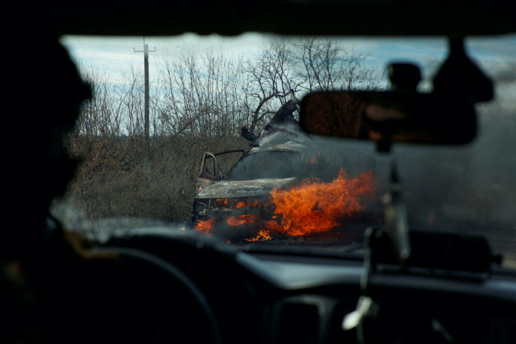 Ukrainian servicemen move past a burning car hit by a kamikaze drone outside the front line town of Avdiivka, amid Russia's attack on Ukraine, in Donetsk region, Ukraine, on 8th November, 2023.