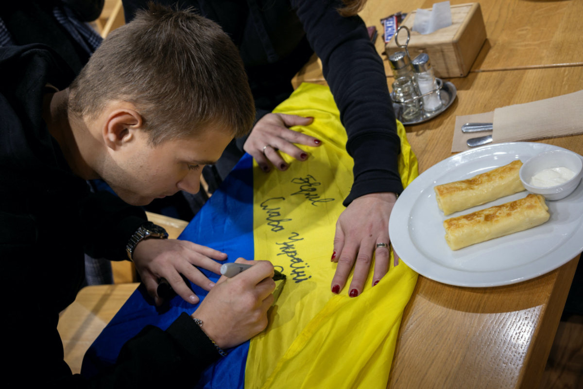 Bohdan Yermokhin, a Ukrainian teenager who was taken to Russia from the occupied city of Mariupol, signs the Ukrainian flag after arriving in his home country from Belarus at a rest stop in Rivne, amid Russia's ongoing attack on Ukraine, on 19th November, 2023