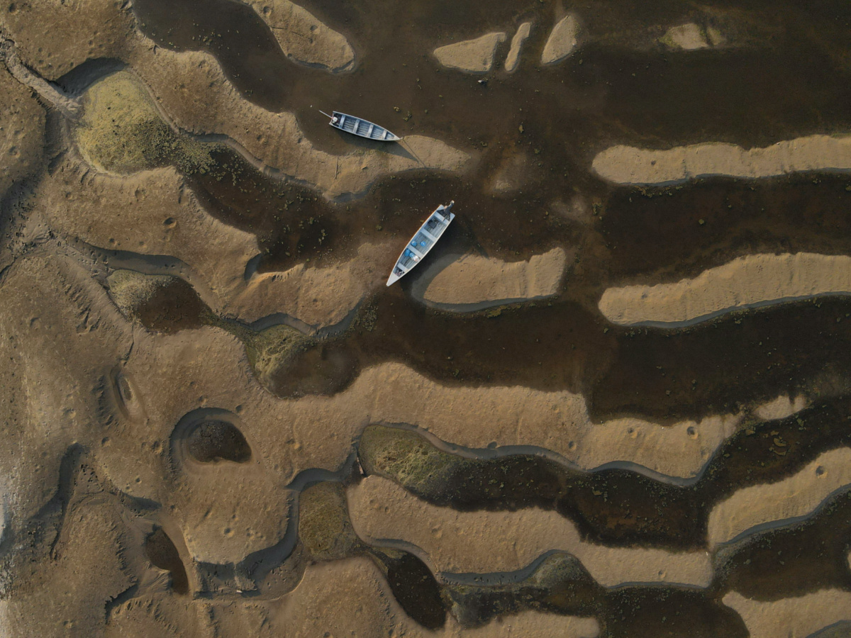 Canoes are seen at the dry riverbed of the Paraua river during a historic drought in the Amazon, in Careiro da Varzea, Amazonas state, Brazil, on 26th October, 2023