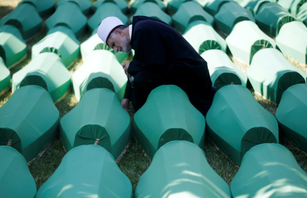 Muslim effendi sits near coffins of his relatives, who are newly identified victims of the 1995 Srebrenica massacre, which are lined up for a joint burial in Potocari near Srebrenica, Bosnia and Herzegovina on 11th July, 2016