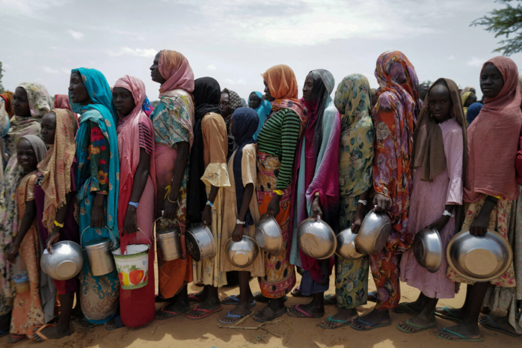 Sudanese women who fled the conflict in Geneina in Sudan's Darfur region, line up to receive rice portions from Red Cross volunteers in Ourang on the outskirts of Adre, Chad on 25th July, 2023