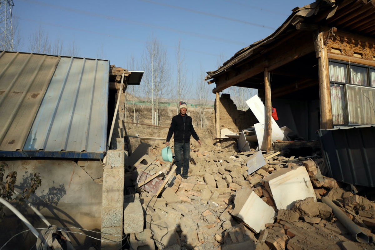 A man walks on the rubble next to a damaged house following the earthquake that rocked Gansu's Jishishan county, in Haidong, Qinghai province, China, on 20th December, 2023