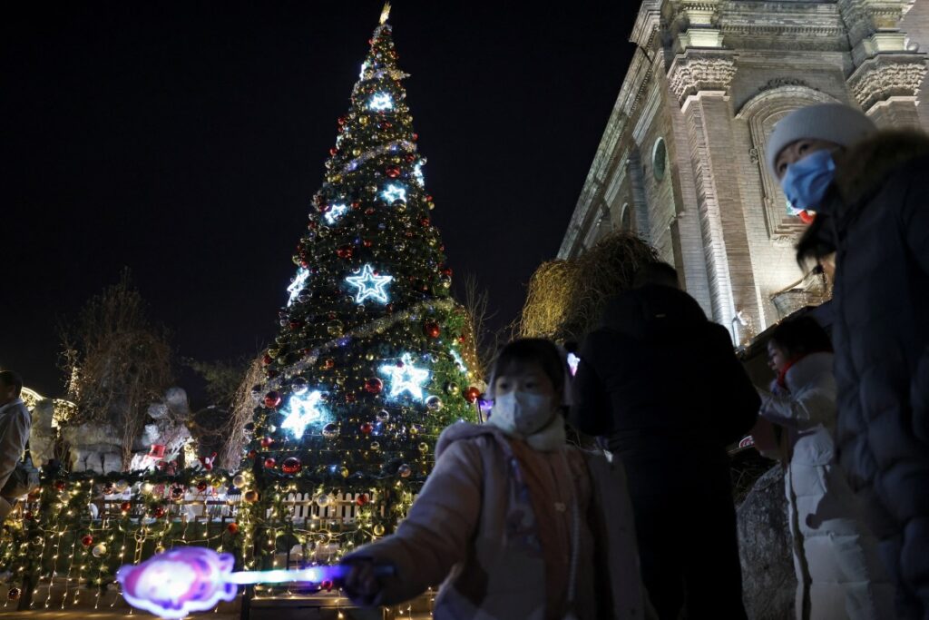A child holds a toy near a Christmas tree outside the South Cathedral, a Catholic church at Xuanwumen, on Christmas Eve in Beijing, China on 24th December, 2023