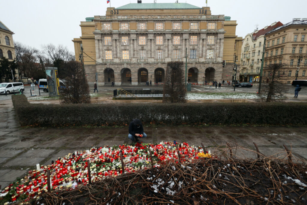 A man lights a candle in the square by university buildings, as people observe national mourning day following a shooting at one of Charles University's buildings, in Prague, Czech Republic, on 23rd December, 2023