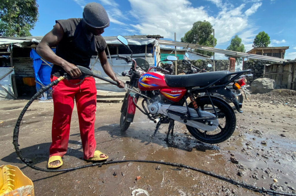 Ishara Bahati Yassin, 20, an internally displaced Congolese from Kibumba, works at his motorbike washing bay business, in Munigi, near Goma, North Kivu province of the Democratic Republic of Congo, on 7th December, 2023
