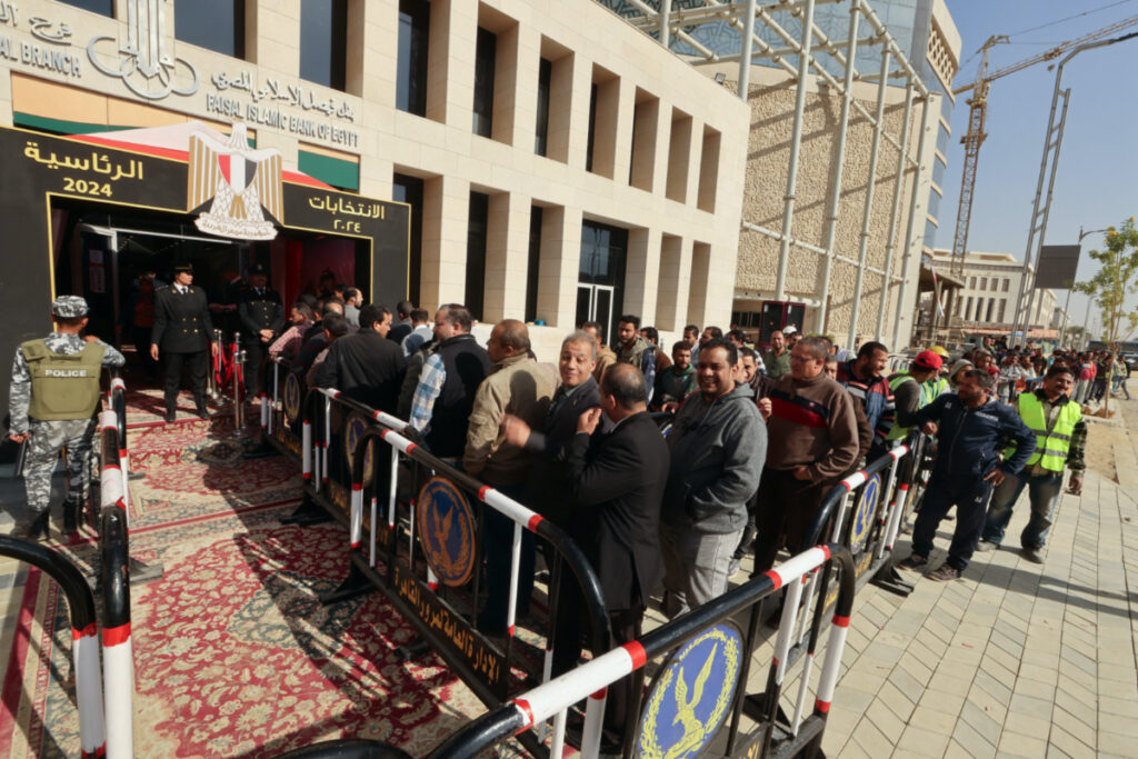 People stand next to a polling station on the second day of the presidential election in the New Administrative Capital, east of Cairo, Egypt, on 12th December, 2023.
