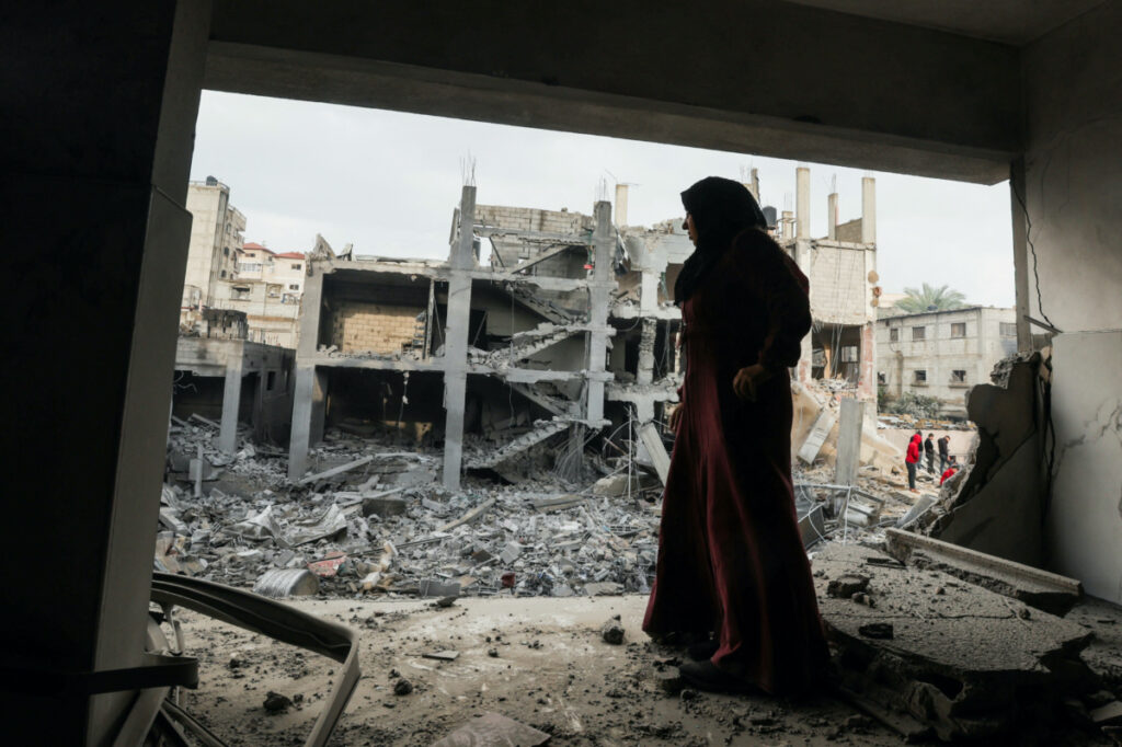 A Palestinian woman stands at the site of Israeli strikes on houses in Khan Younis, in the southern Gaza Strip on 14th December, 2023