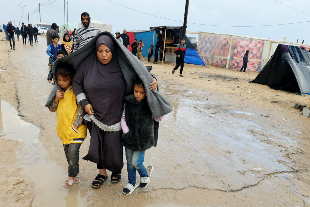 Displaced Palestinians, who fled their houses due to Israeli strikes, walk following heavy rains at tent camps, as the conflict between Israel and Hamas continues, in Rafah, in the southern Gaza Strip on 13th December, 2023.