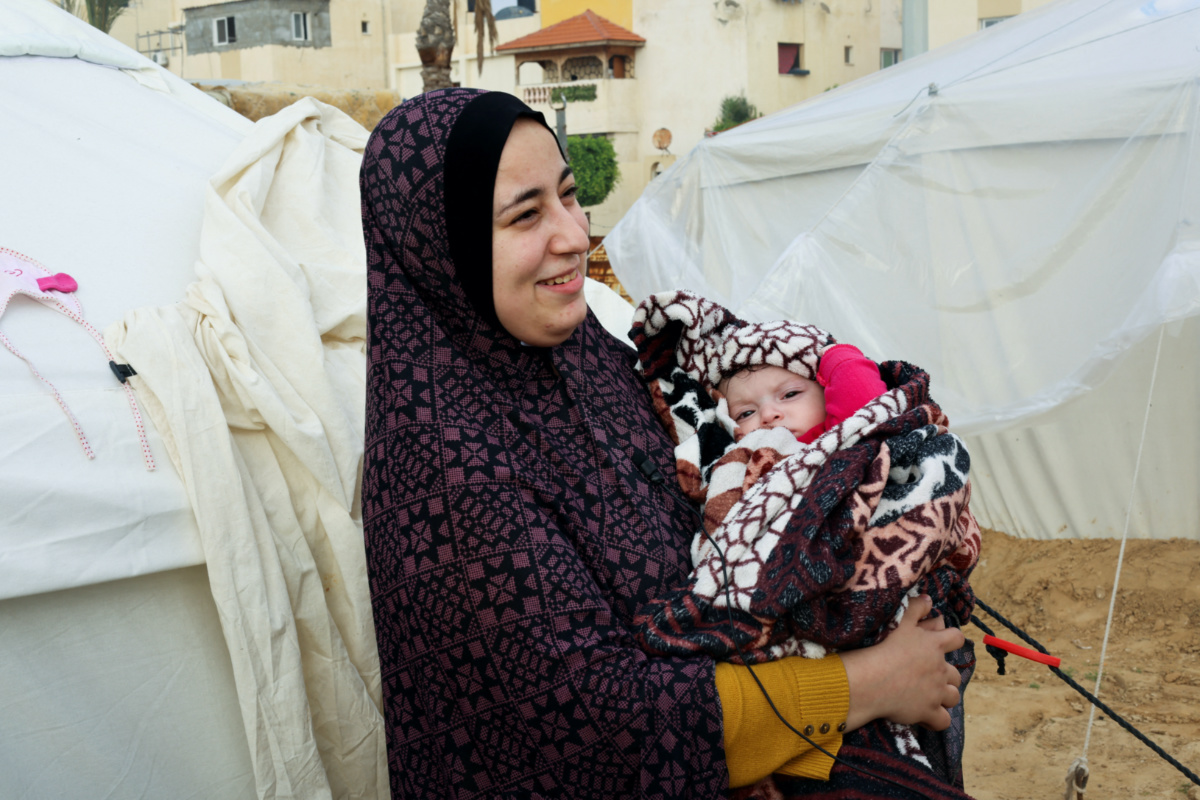 Palestinian mother Yasmine Saleh holds her baby daughter Toleen, who was war born during the conflict between Israel and Hamas, outside their tent where they shelter with their displaced family who fled their house due to Israeli strikes, in Rafah in the southern Gaza Strip on 17th December, 2023