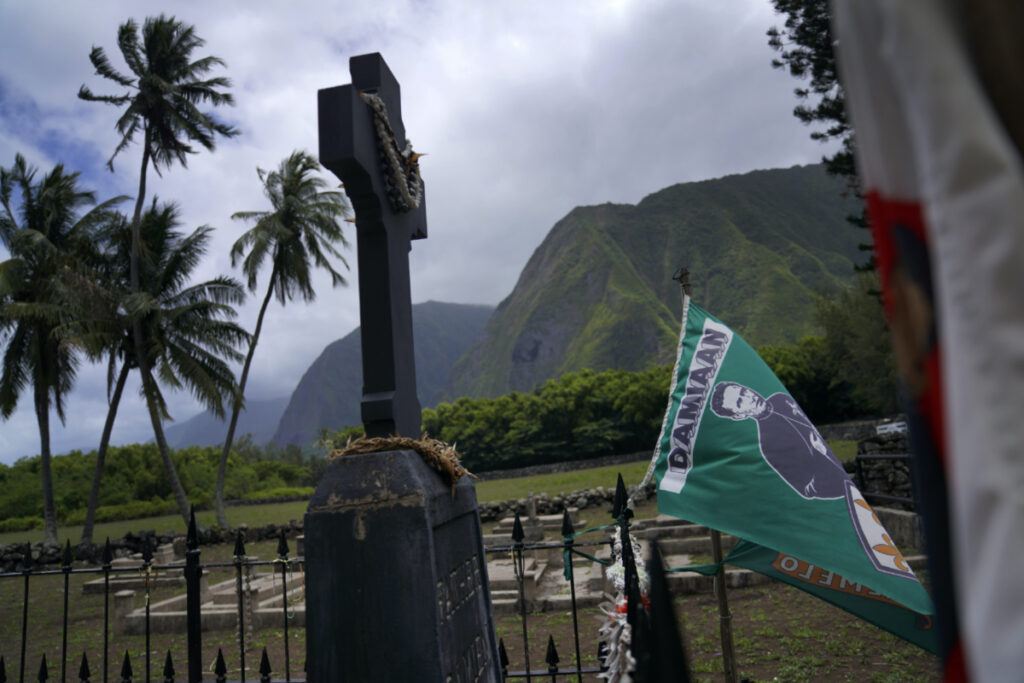 Flags blow in the breeze at the grave of Father Damien outside St Philomena Church on Kalaupapa, Hawaii, on Tuesday, 18th July, 2023.