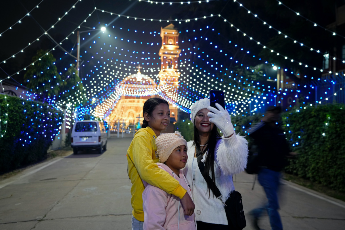 People take selfies in front of the decorated St Joseph's Cathedral on the eve of Christmas in Prayagraj, India, on Sunday, 24th December, 2023