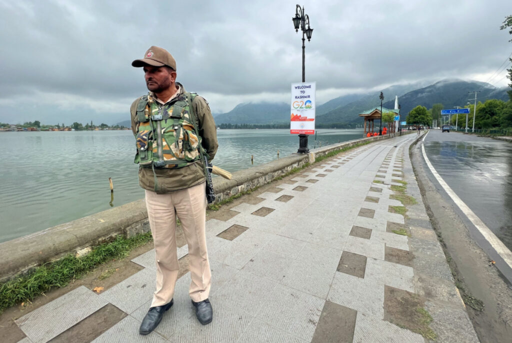 A police officer stands guard along the banks of Dal Lake near the venue of the G20 tourism working group meeting in Srinagar on 24th May, 2023
