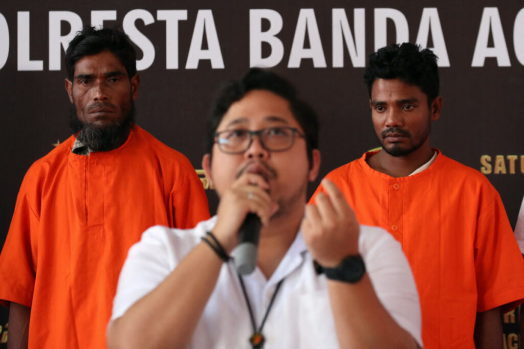 Two suspects, a Bangladesh national and a Rohingya, stand while an Aceh police official, Fadillah Aditiya Pratama speaks during a news conference, after smuggling at least 400 Rohingyas refugees in early December, at a police office in Banda Aceh, Aceh province, Indonesia, on 27th December, 2023